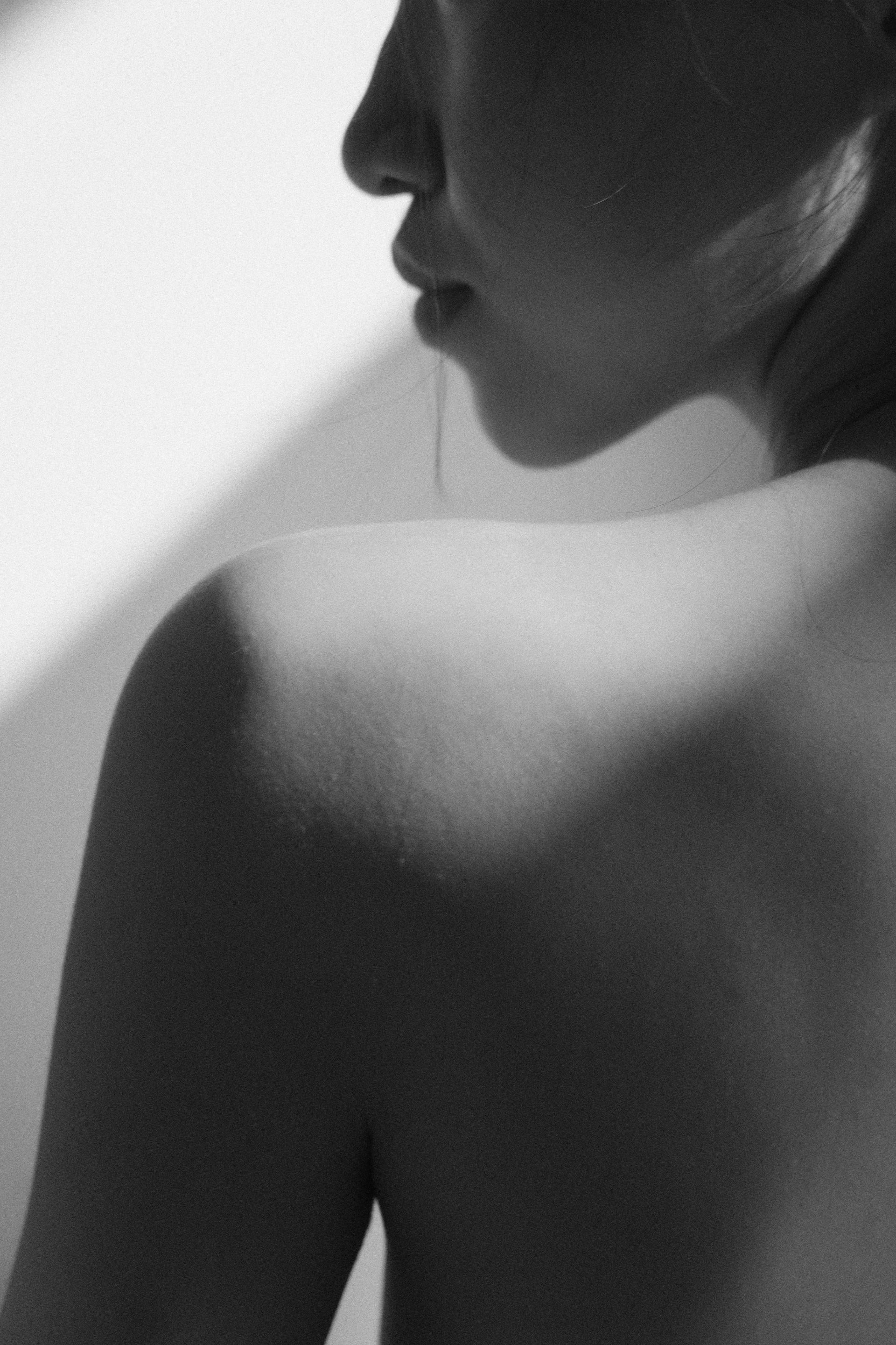 Eine Schwarz-Weiß-Nahaufnahme im Profil, die die Schulter und den unteren Teil des Gesichts einer Person zeigt und die entspannte Atmosphäre der Spa-Behandlungen in Zürich vermittelt.